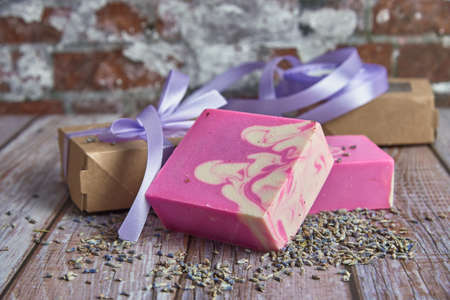 Fragrant pink organic handmade soap, gift box decorated with silk ribbon and dried flowers on the wooden countertop. Healthy lifestyle, eco-friendly products.の写真素材