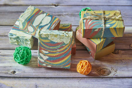 Several pieces of multicolored handmade organic soap and various decorations on a light gray background.の写真素材