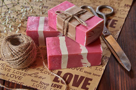Fragrant pink organic handmade soap and household items on packaging paper with the inscription love.の写真素材