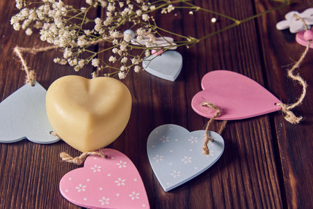 A fragrant organic handmade soap in the shape of a heart, with wooden decor and flowers on a dark background.の写真素材