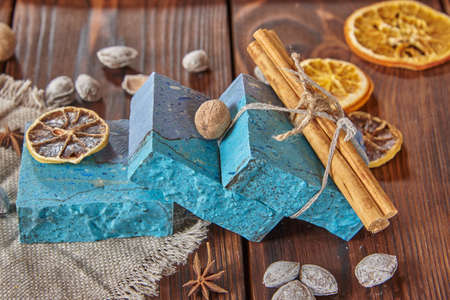 A fragrant, bright blue organic handmade soap, a linen napkin, and scented spices on a brown wooden countertop.の写真素材