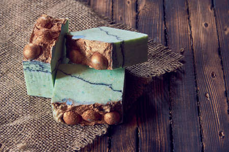 A fragrant green organic handmade soap and burlap on a brown wooden countertop.の写真素材