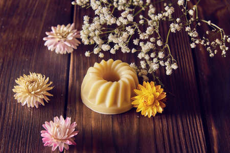 Fragrant organic handmade soap of unusual shape and dried flowers on a dark wooden countertop.の写真素材