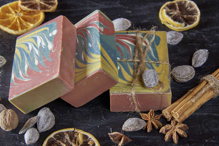 Fragrant multicolored organic handmade soap, nuts and scented spices on a dark slate background.の写真素材