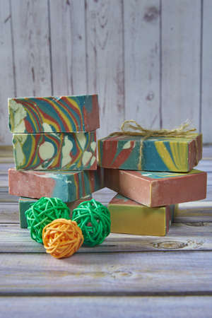Several pieces of multicolored handmade organic soap and various decorations on a light gray background.の写真素材