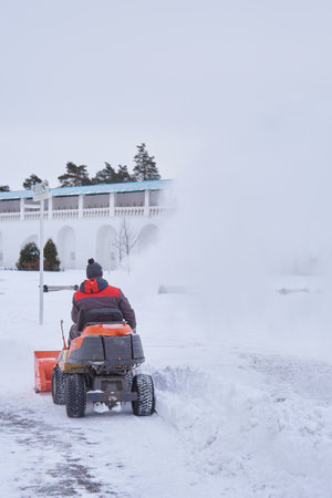Russia, Moscow region, February 2021.A warmly dressed man on a snow plow removes snow on the territory of the monastery on a frosty day.のeditorial素材