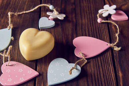 A fragrant organic handmade soap in the shape of a heart with wooden decor on a dark background.の写真素材