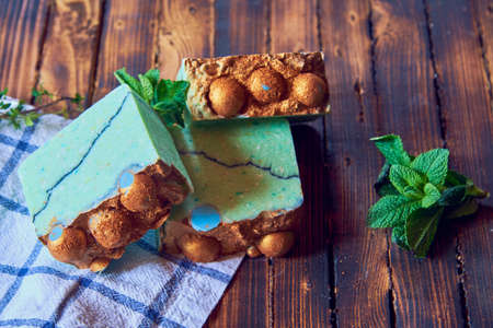 A fragrant green organic handmade soap decorated with mint leaves and a kitchen towel on a brown wooden countertop.の写真素材