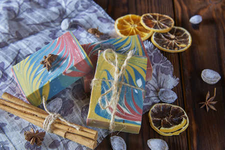 Bright multicolored handmade soap, aromatic spices and a linen napkin on the dark wooden countertop.の写真素材