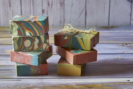 Several pieces of multicolored handmade organic soap and various decorations on a light gray background.の写真素材