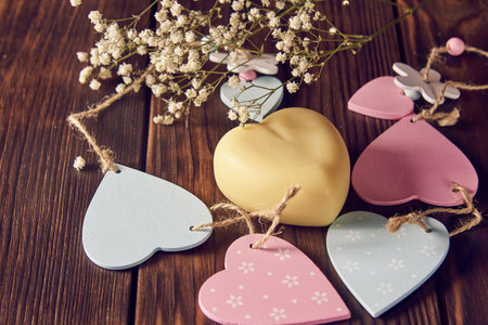 A fragrant organic handmade soap in the shape of a heart, with wooden decor and flowers on a dark background.の写真素材