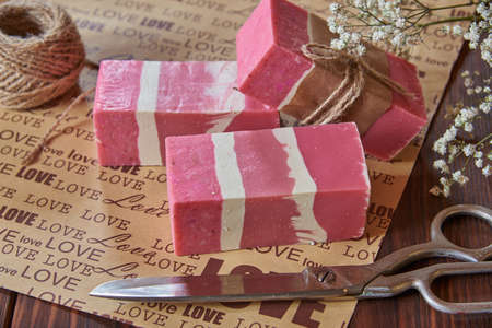 Fragrant pink organic handmade soap and household items on packaging paper with the inscription love.の写真素材