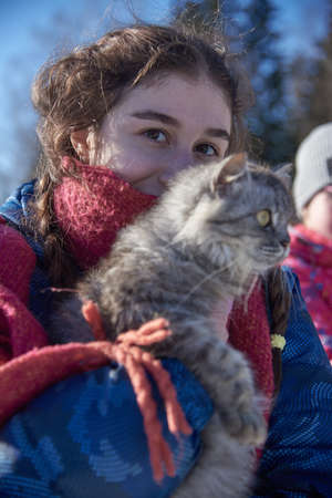 Focus on the girl's face.A fluffy gray cat with huge eyes in the girl's arms.の写真素材