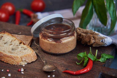 Handmade chicken pate in a glass jar on a wooden board.の写真素材