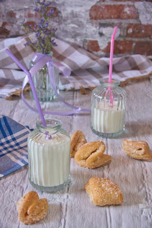 Light still life. Curd sugar cookies and milk cans on a white brick countertop.の写真素材