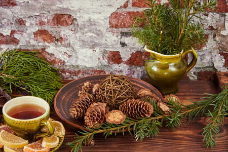 A vintage ceramic teacup sits on a wooden countertop decorated with fir branches and cones.の写真素材