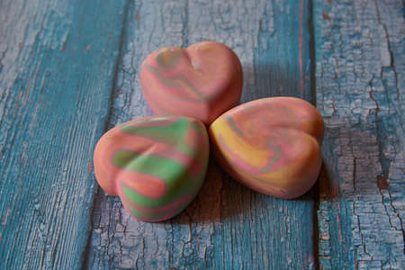Fragrant multicolored organic handmade soap in the shape of a heart on a blue wooden background.