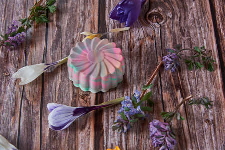 Bright organic handmade scented soap in the shape of a flower and spring flowers on a wooden background.の写真素材