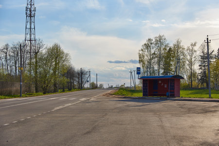 A paved country road and an old bus stop on a cloudy spring day.の写真素材