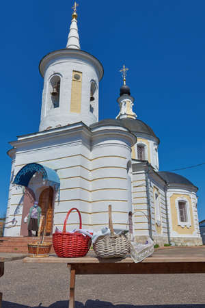 Wicker baskets with eggs and cakes stand on a bench in front of the church on the feast of Bright Easter.の写真素材