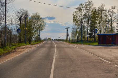 A paved country road and an old bus stop on a cloudy spring day.の写真素材