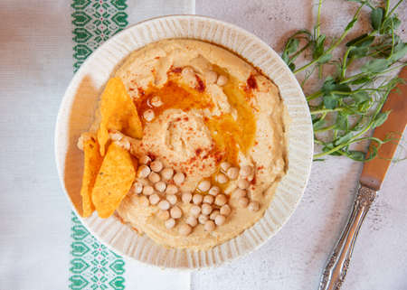 Chickpea hummus flavored with olive oil and sweet paprika and corn nachos on a gray background.の写真素材