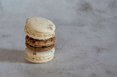Coffee and vanilla macaroon are stacked in a pyramid on a light gray background. Copy space for...