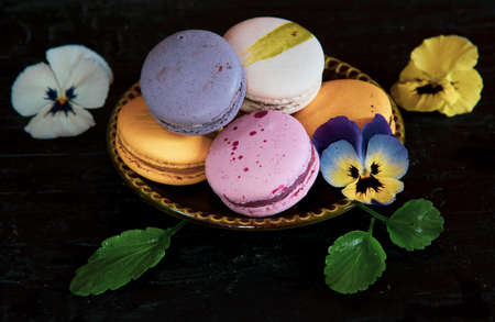 Colorful, delicious pasta lies on a green ceramic saucer decorated with bright pansies. On a dark background.の写真素材