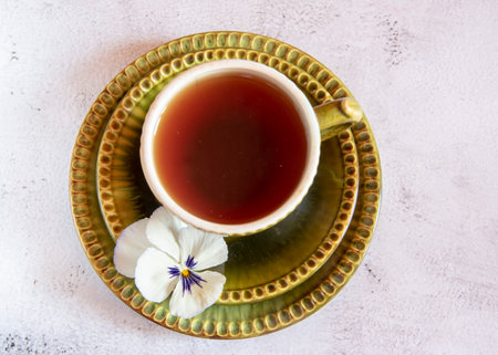 One green ceramic tea cup and two saucers decorated with flowers on a light background. Top view. Focus on the flower.の写真素材