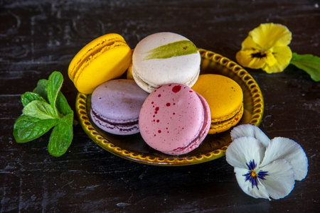Colorful, delicious pasta lies on a green ceramic saucer decorated with bright pansies. On a dark background.の写真素材