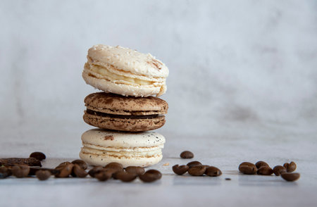 Coffee and vanilla macaroon are stacked in a pyramid on a light gray background. Decorated with coffee beans.Copy space for text, design.の写真素材