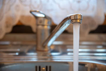 Sink with a tap in a kitchen. Kitchen faucet with running water.の写真素材