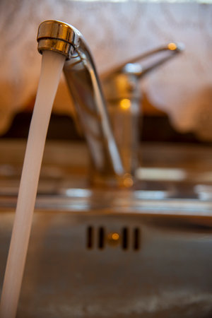 Sink with a tap in a kitchen. Kitchen faucet with running water.の写真素材