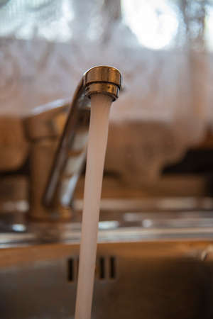 Sink with a tap in a kitchen. Kitchen faucet with running water.の写真素材
