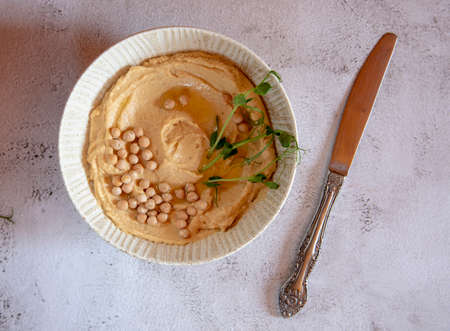A plate of hummus, seasoned with butter, garnished with chickpeas, on a tabletop .の写真素材