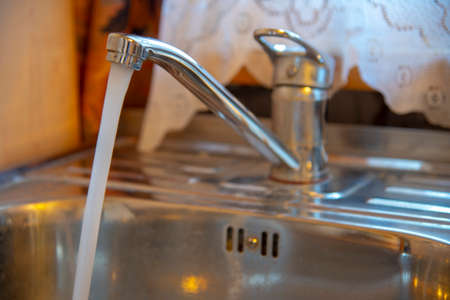 Sink with a tap in a kitchen. Kitchen faucet with running water.の写真素材