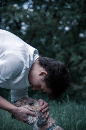 A teenage boy hugs his furry dog on a walk. Irish Soft Coated wheaten terrier.の写真素材