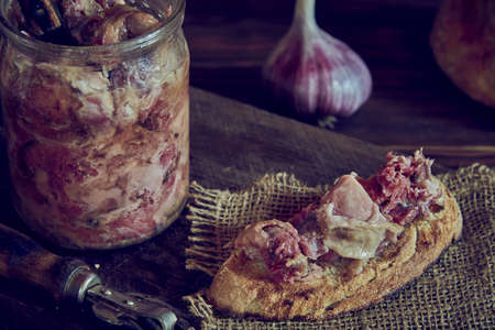 A glass jar with homemade stew and an appetizing sandwich on a wooden cutting board. Food backgrounds. Photo in a low key.の写真素材