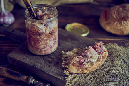 A glass jar with homemade stew and an appetizing sandwich on a wooden cutting board. Food backgrounds. Photo in a low key.の写真素材