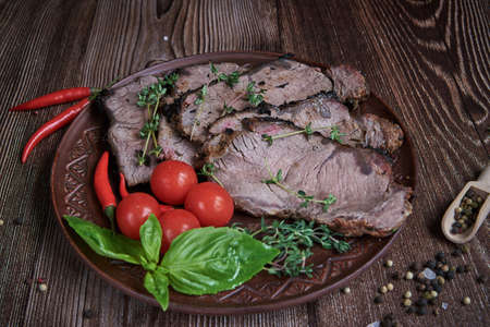 Sliced pieces of fried meat on a clay plate, decorated with spicy herbs. Food backgrounds.の写真素材