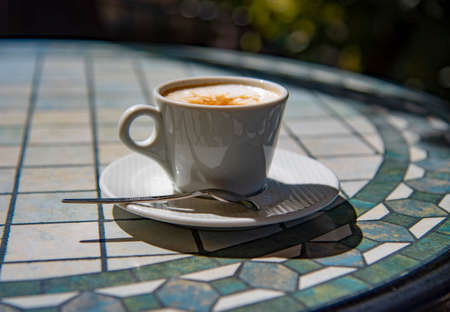 A cup of cappuccino on a table in a summer cafe on a sunny day.の写真素材