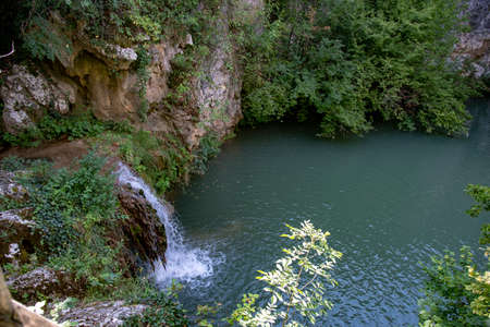 Mountain waterfall. Powerful jets of water flow into the lake, illuminated by the sun. Summer landscape.の写真素材