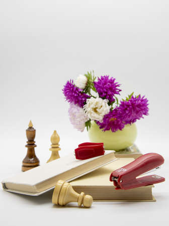 A composition of flowers in a vase, books and various educational accessories on a light background....