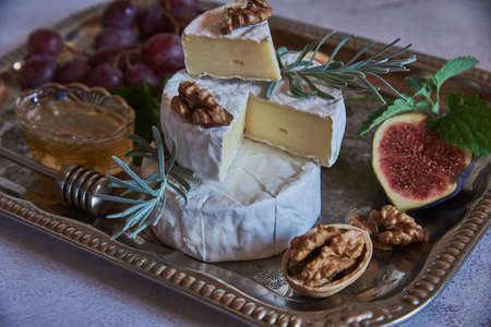 Cheese with white mold with herbs, nuts and fruits on a silver tray.の写真素材