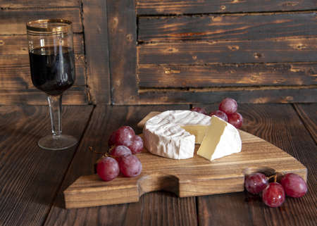 Cheese with white mold and grapes on a wooden cutting board. Food background.の写真素材