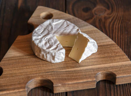 Cheese with white mold lies on a wooden cutting board.の写真素材