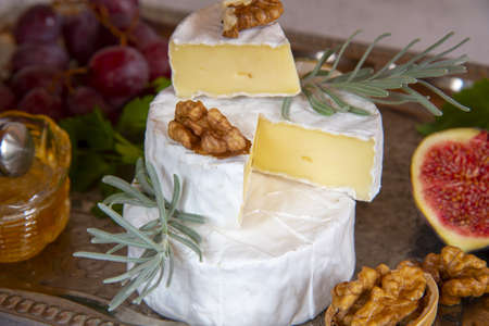 Cheese with white mold with herbs, nuts and fruits on a silver tray.の写真素材