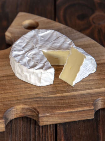 Cheese with white mold lies on a wooden cutting board.の写真素材