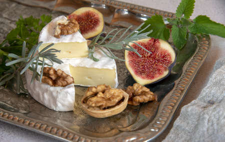 Cheese with white mold with herbs, nuts and fruits on a silver tray.の写真素材