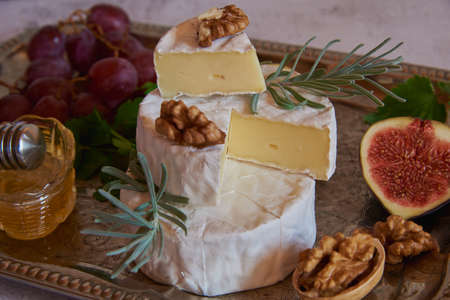 Cheese with white mold with herbs, nuts and fruits on a silver tray.の写真素材